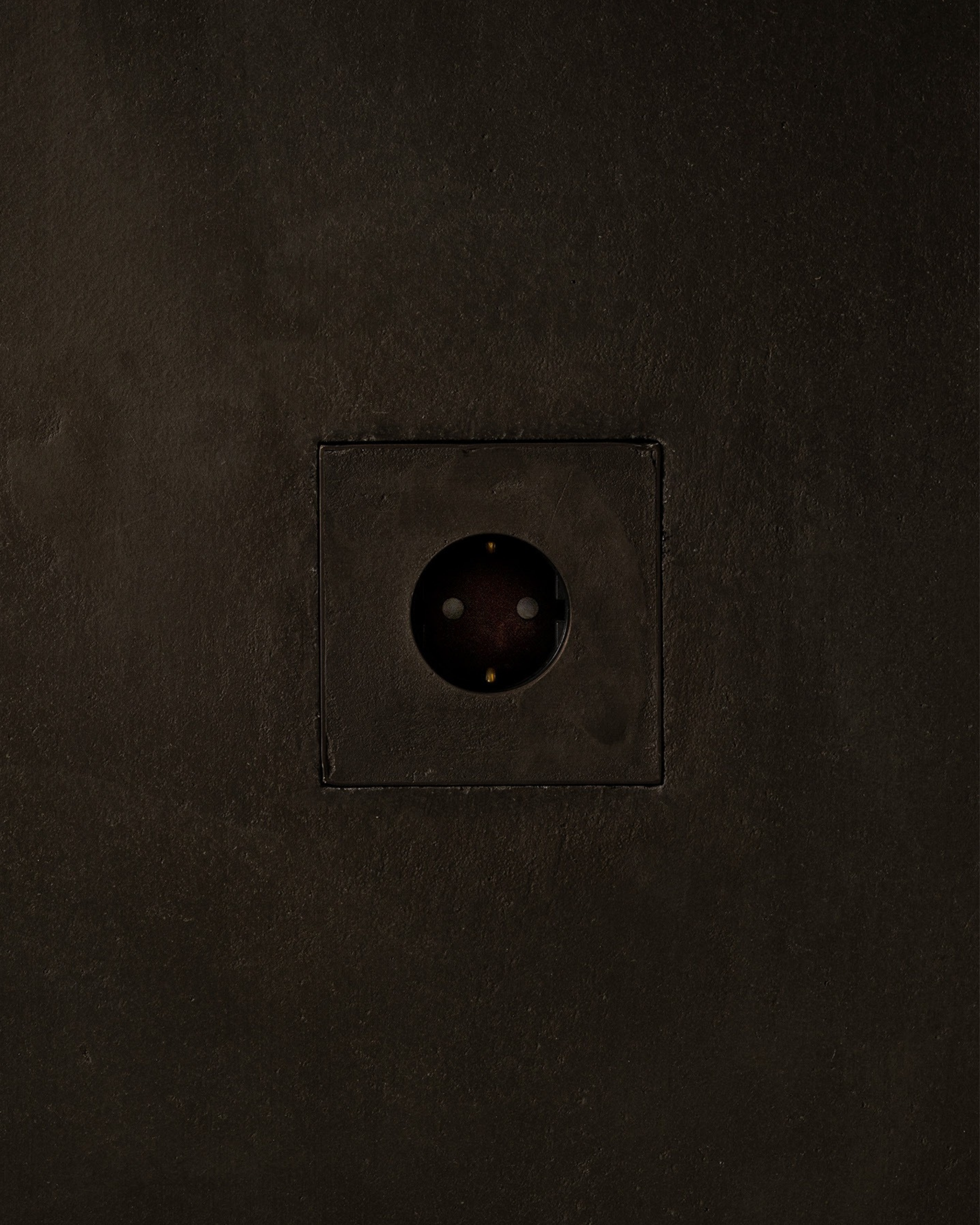 MATA recessed single power outlet seamlessly integrated into a dark textured plaster wall – Sumum x Studio STRAF. This socket is curated by Numa Home for the Netherlands and Türkiye.