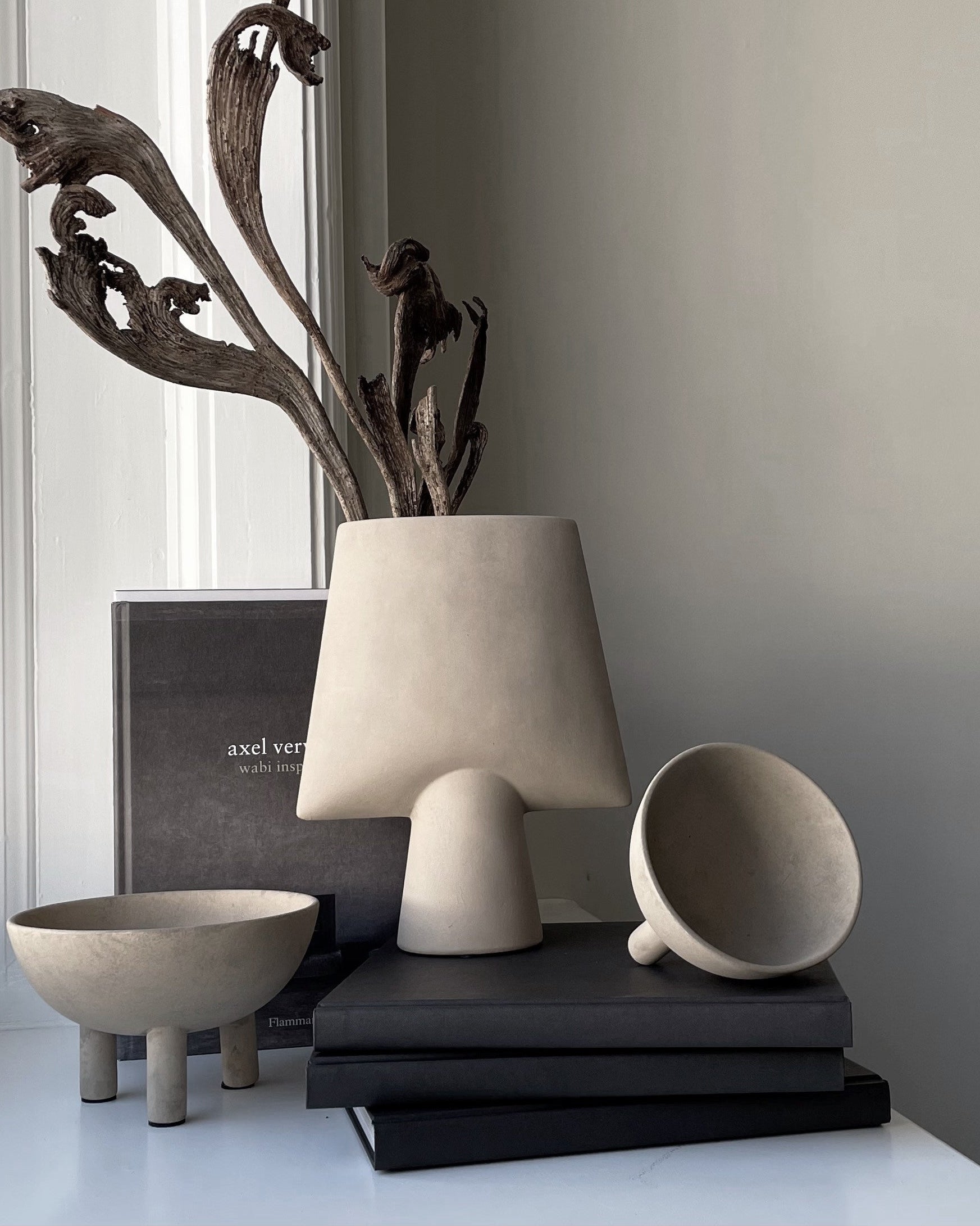 Decorative items including a vase, cup, and books on a surface with a neutral background.