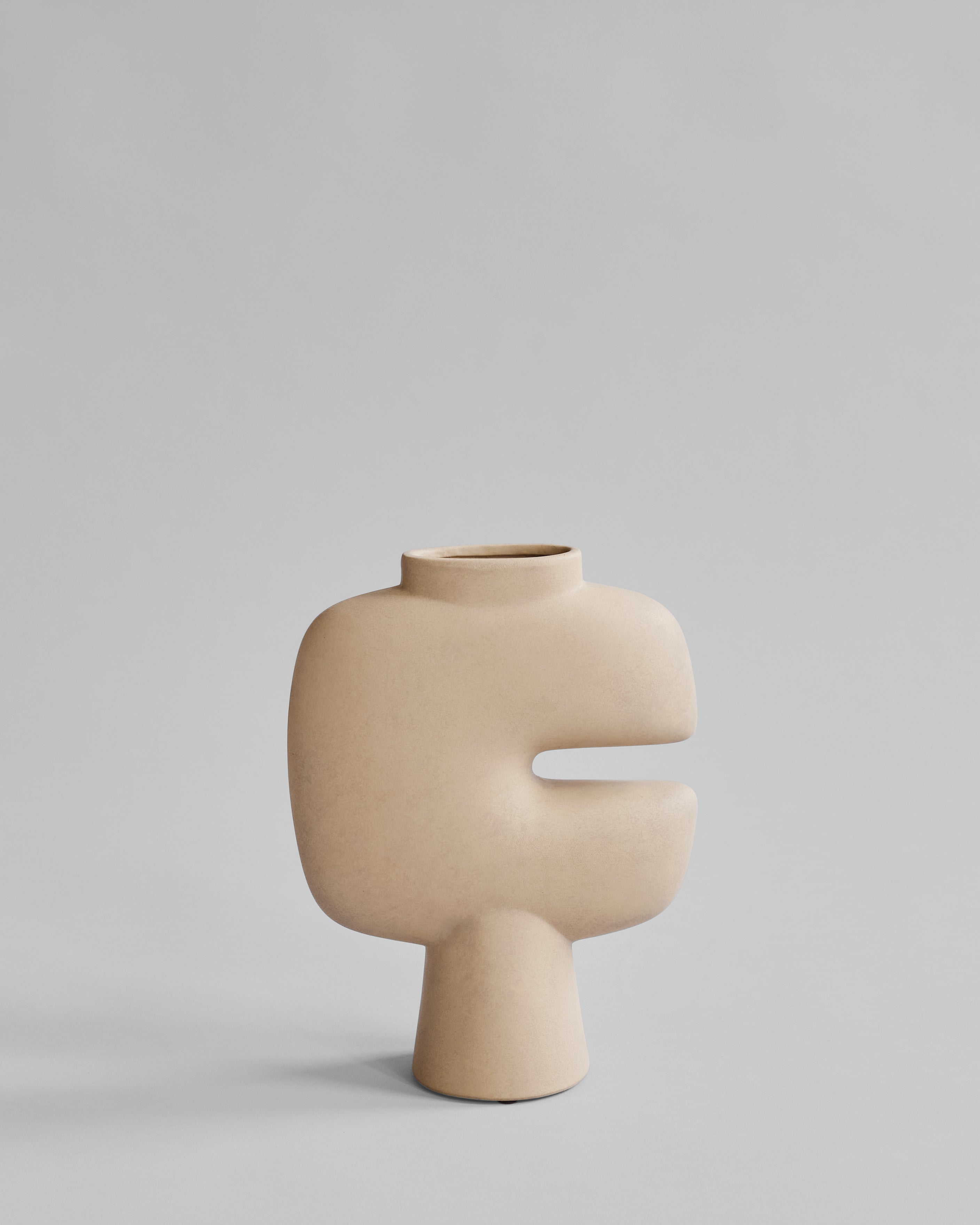 Beige ceramic vase with a unique design on a light gray background