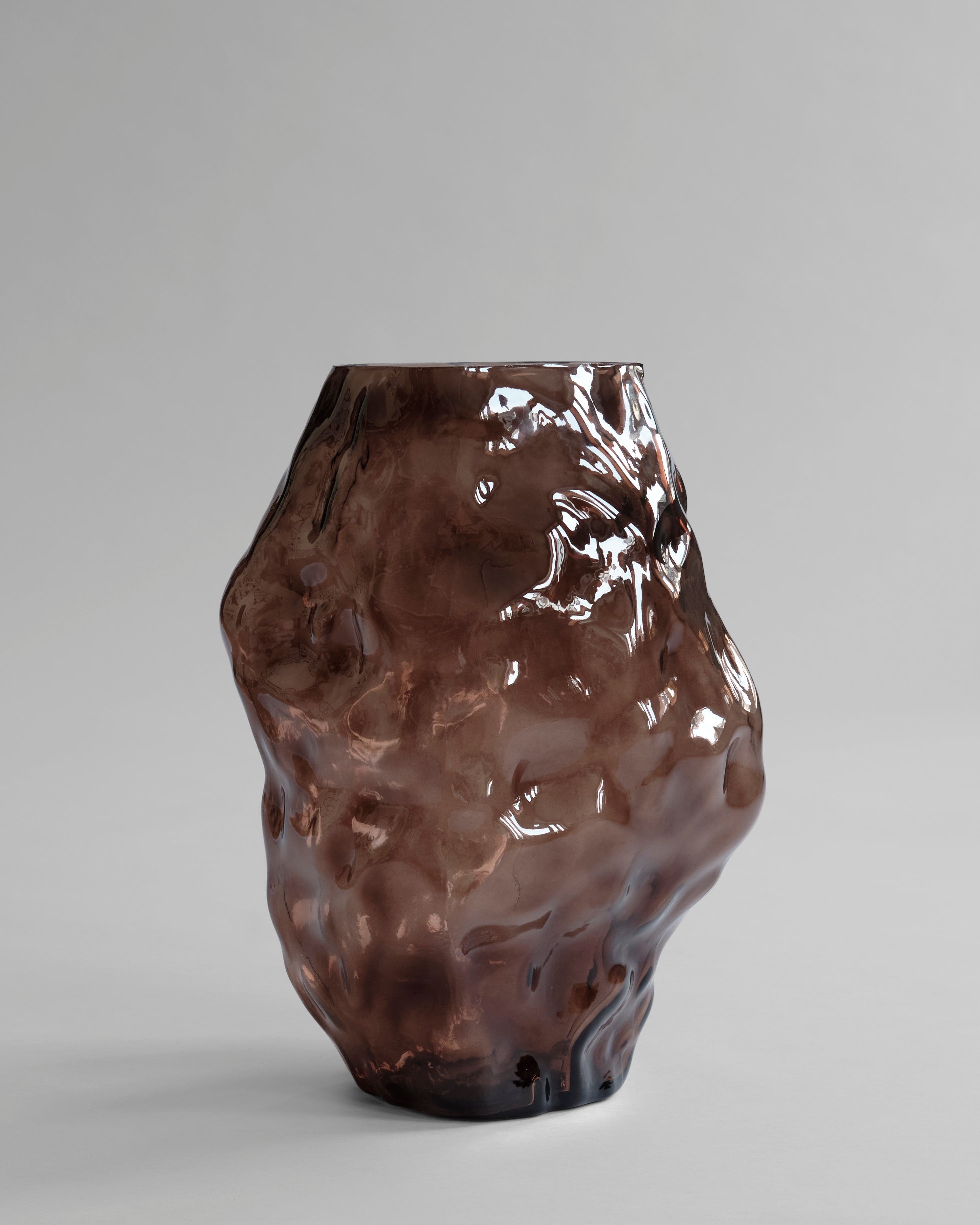 Brown textured vase on a gray background. Katachi Vase, Big by 101 Copenhagen. Sculptural vase inspired by Japanese “shape”, available in High Glaze Birch ceramic and Clear or Smoked Forest mouth-blown glass. Fully waterproof, curated by Numa Home.