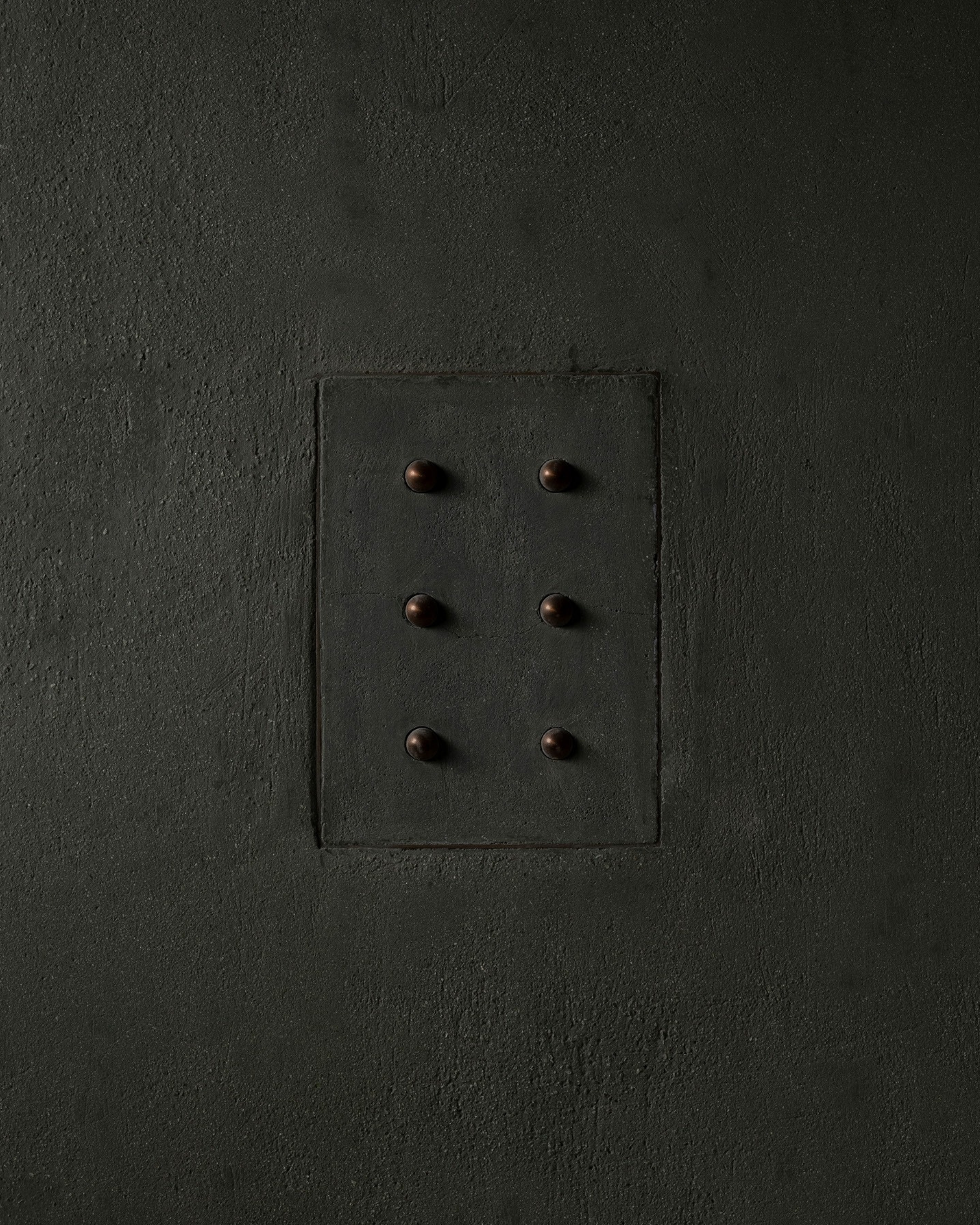 MATA recessed switch with six bullet-shaped button, seamlessly integrated into a dark green colored and rough textured plaster wall – Sumum x Studio STRAF. Curated by Numa Home for the Netherlands and Turkey
