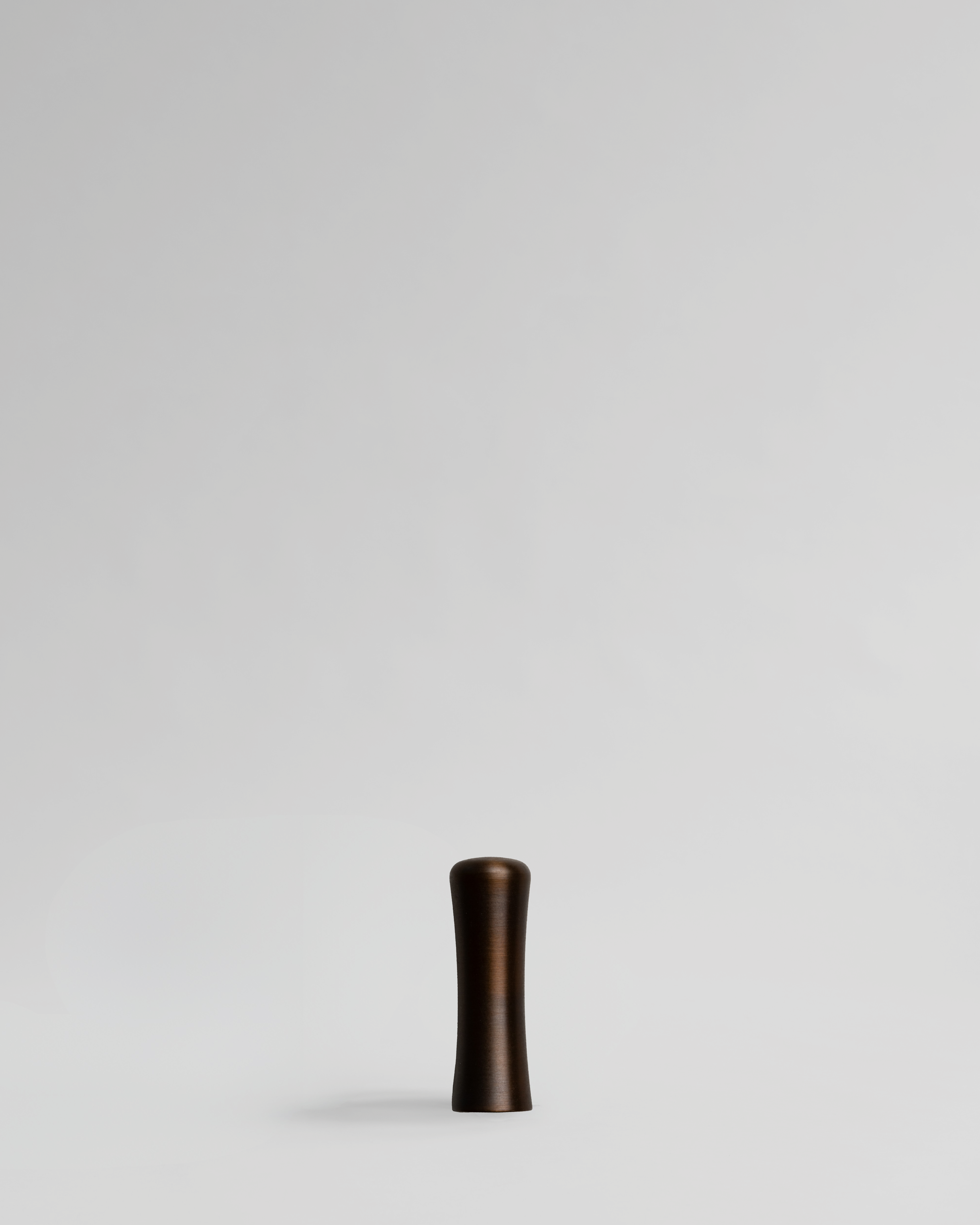 Brass handle on a light gray background. Brass cabinet handle designed by Stef Claes, created by Sumum, curated by Numa Home.