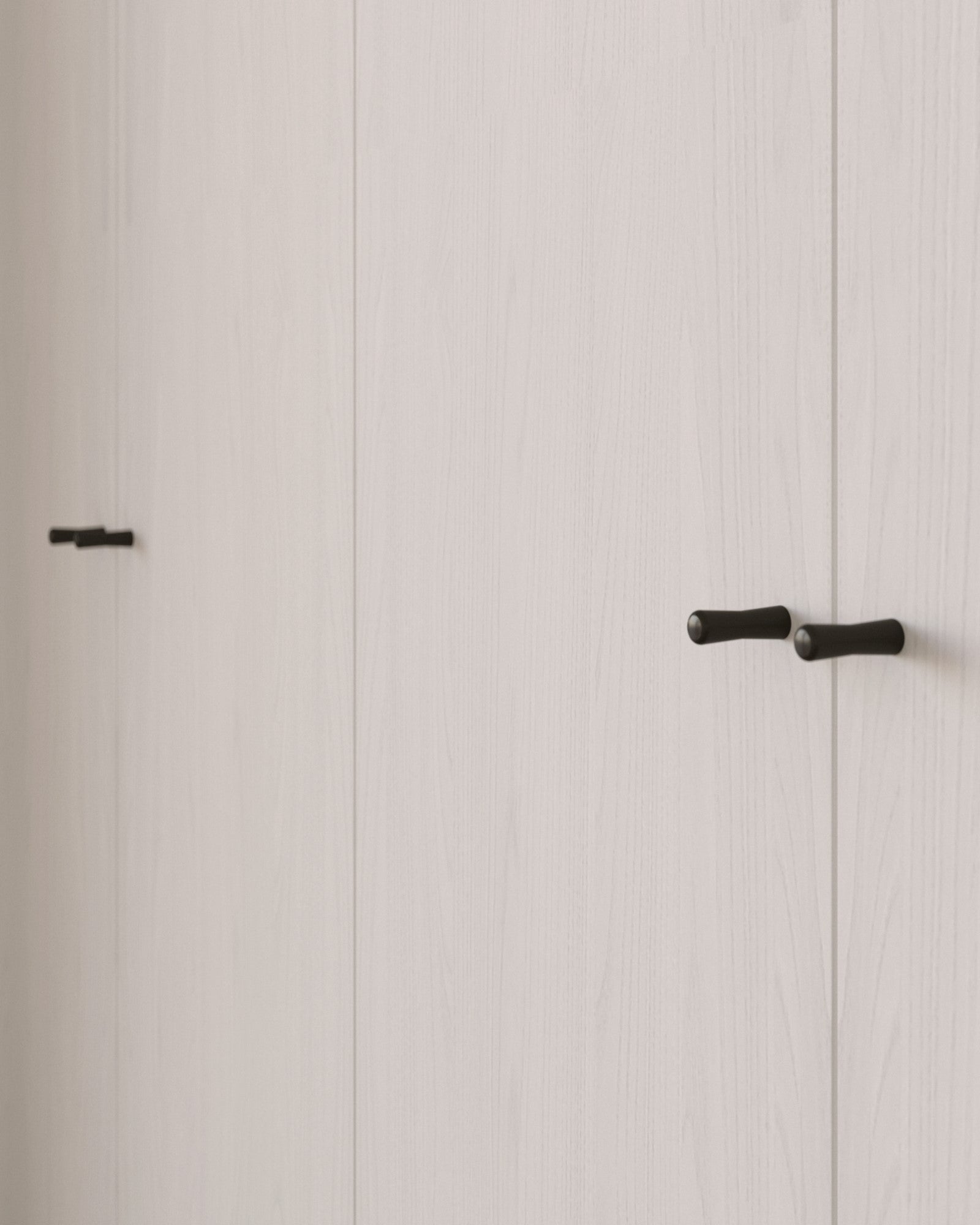 Close-up of a light wooden wardrobe with black SUMUM handles. Brass cabinet handle designed by Stef Claes, created by Sumum, curated by Numa Home.