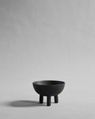 Black ceramic bowl on coffee color by 101 Copenhagen on a gray background