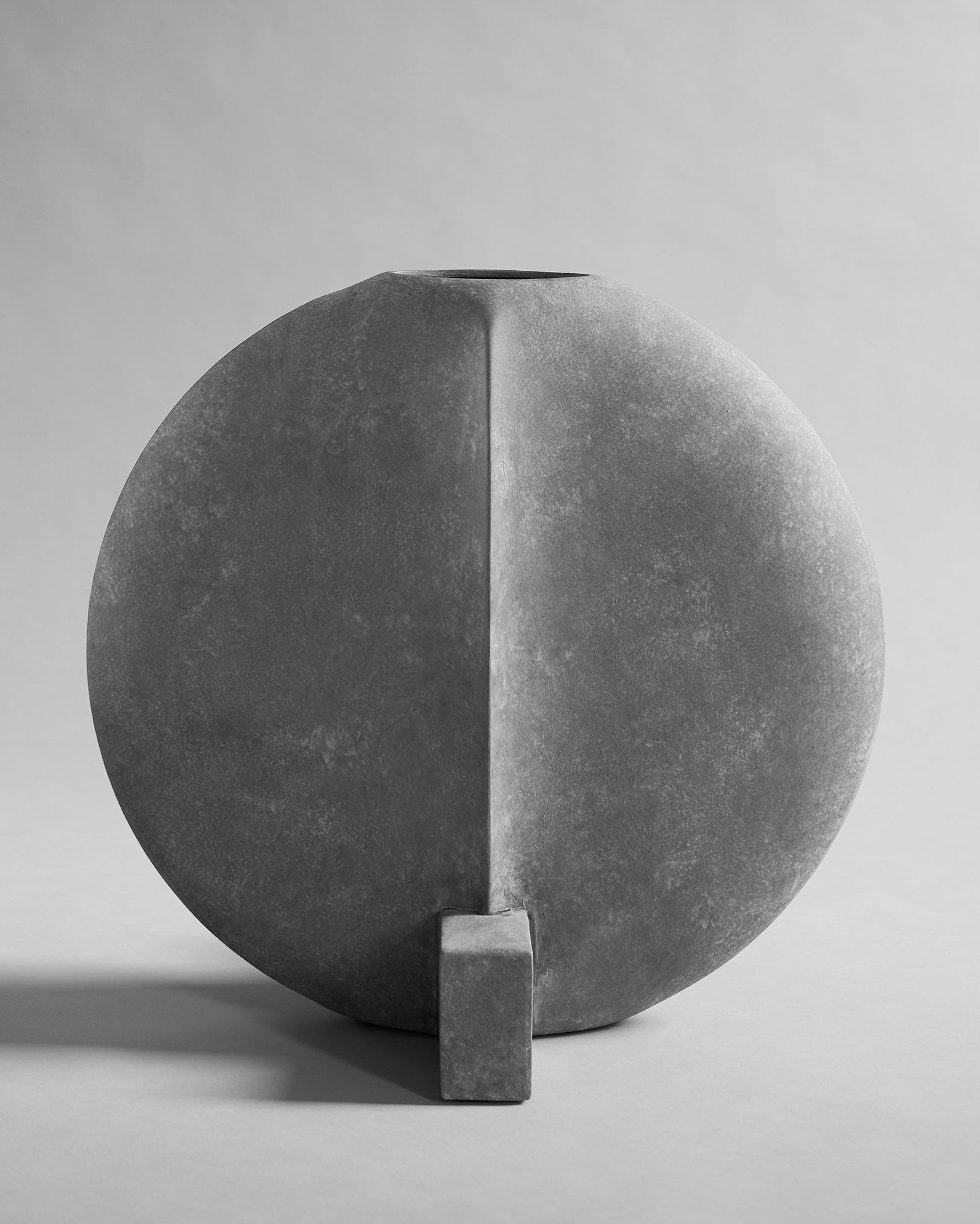 Gray stone sculpture with geometric design on a gray background. Guggenheim Vase by 101 CPH curated by Numa Home