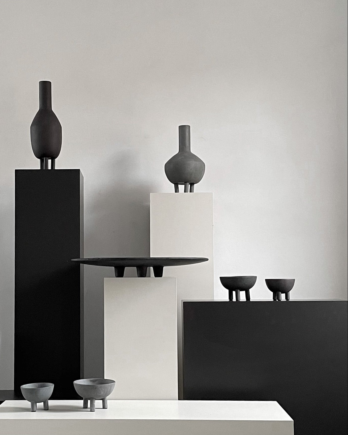 Modern black and gray ceramic vases and bowls on a neutral background