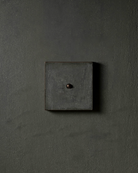 Surface-mounted MATA switch with a single bullet-shaped button on a dark textured wall plaster – Sumum x Studio STRAF. Curated by Numa Home for the Netherlands and Türkiye Markets.
