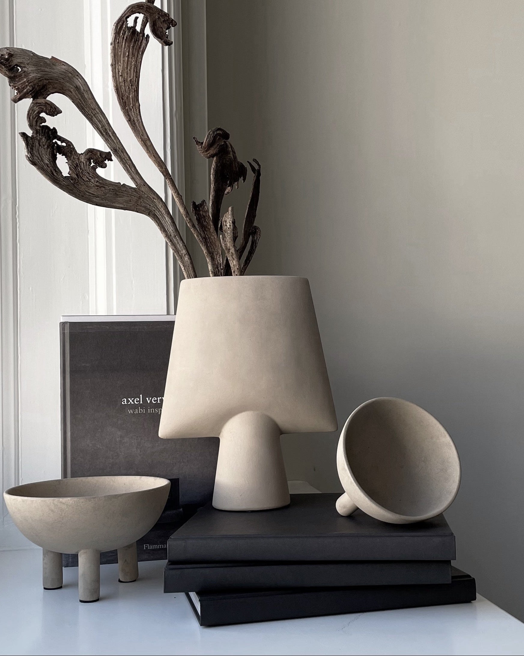 Decorative items including a vase, cup, and books on a surface with a neutral background.