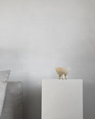 Small ceramic bowl on a white pedestal against a plain background