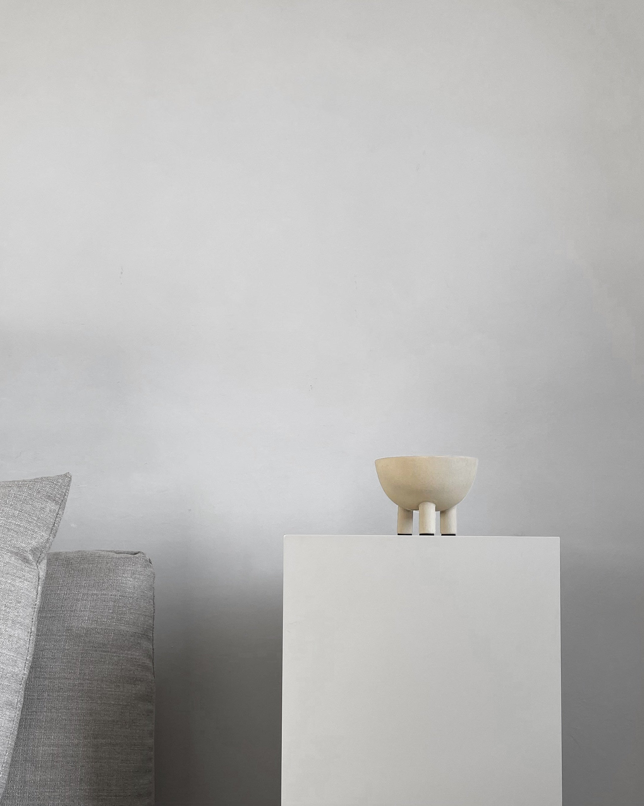 Small ceramic bowl on a white pedestal against a plain background