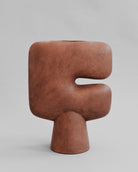 Brown letter 'F' sculpture on a gray background