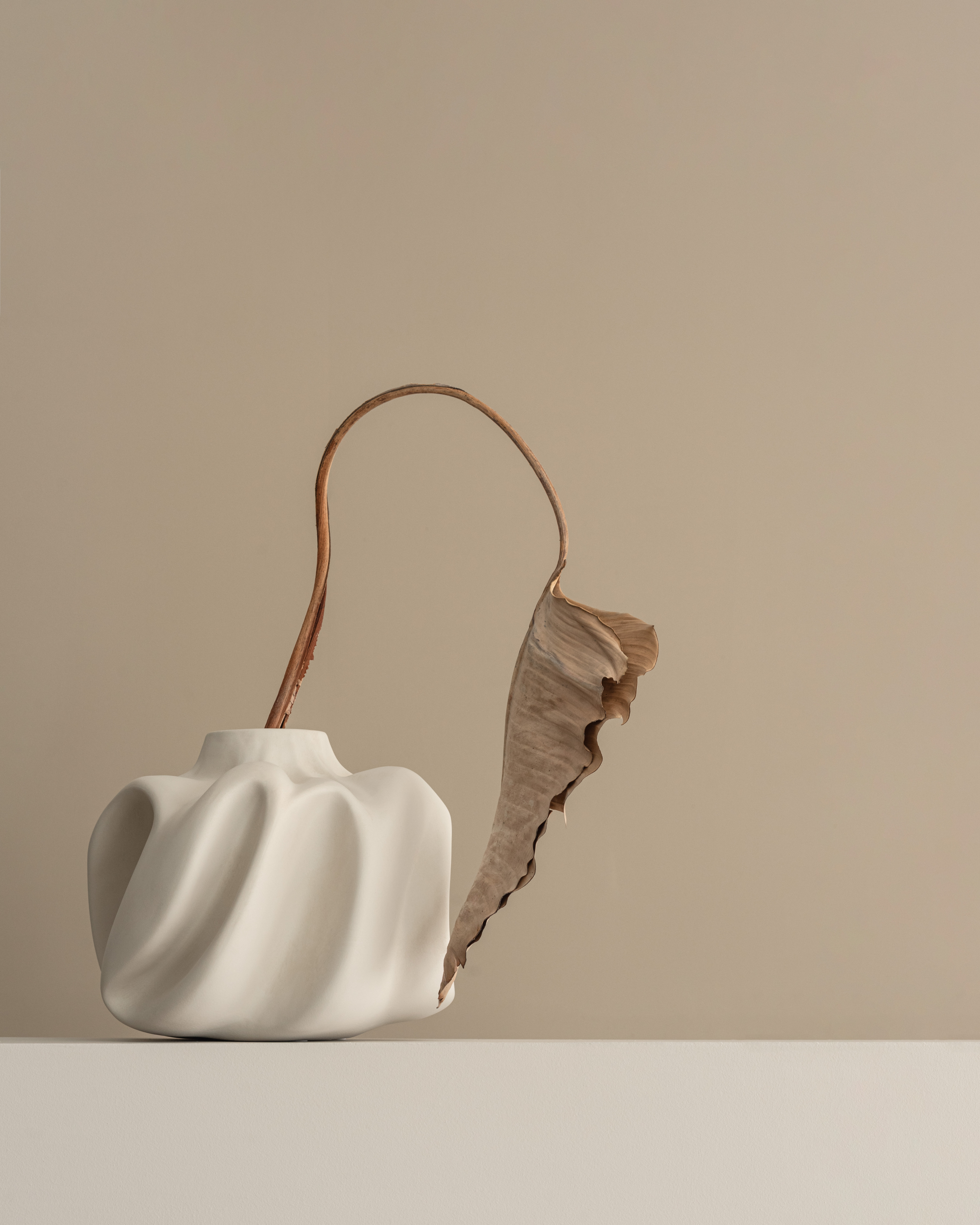 White ceramic vase with a textured handle on a beige background