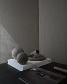Decorative elements on a shelf with books and stones against a plain wall.