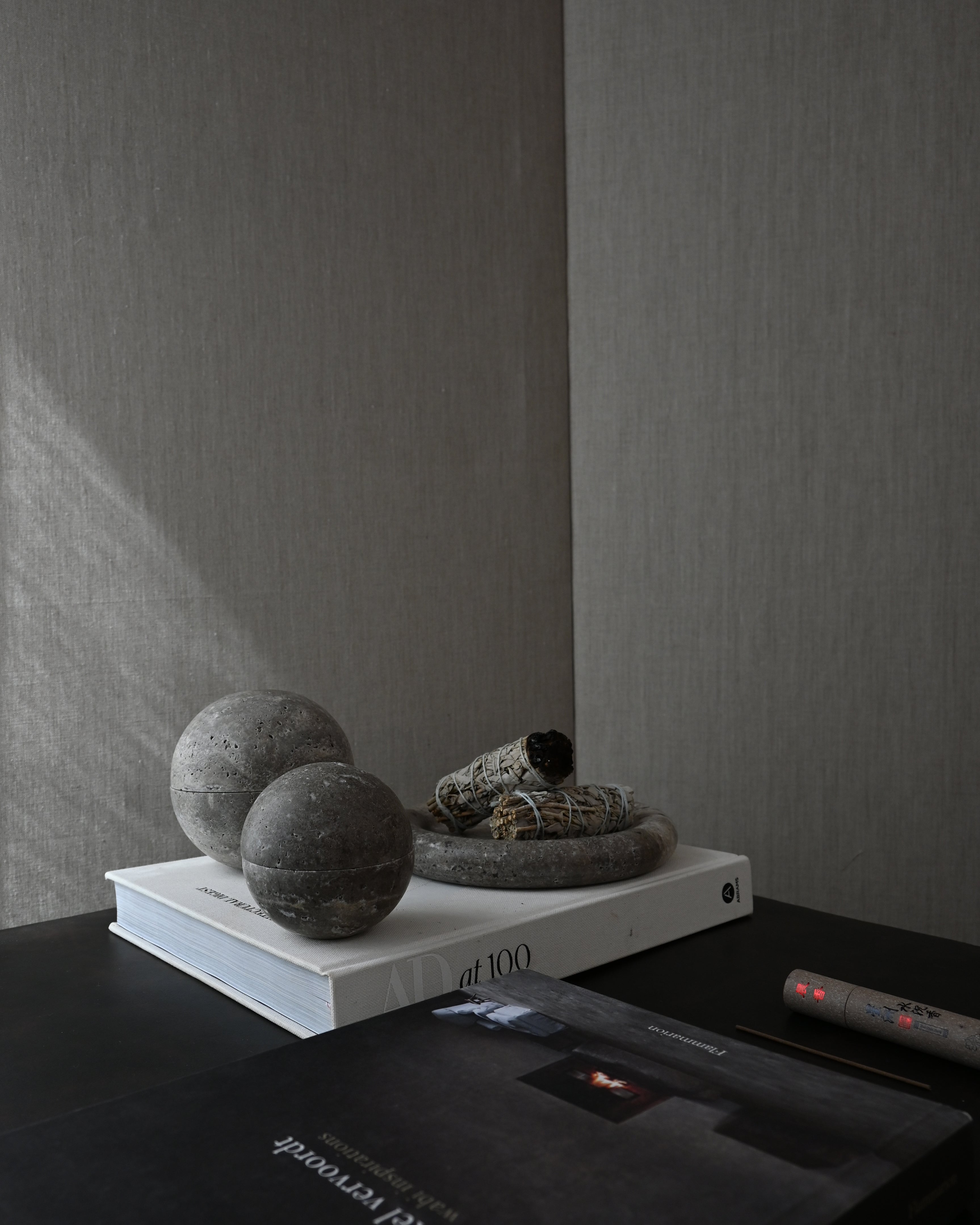 Decorative elements on a shelf with books and stones against a plain wall.