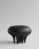 Black, abstract-shaped vase on a light gray background. Medusa Vase, Big by 101 Copenhagen. Sculptural ceramic vase with soft oval shapes and small conical legs, hand-glazed in Coffee. Curated by Numa Home for calm, modern interiors.