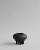 Black vase with unique design on a light gray background. Medusa Vase, Mini by 101 Copenhagen. Sculptural ceramic mini vase in Coffee with soft oval shapes and conical legs, hand-glazed and not 100% waterproof – curated by Numa Home.