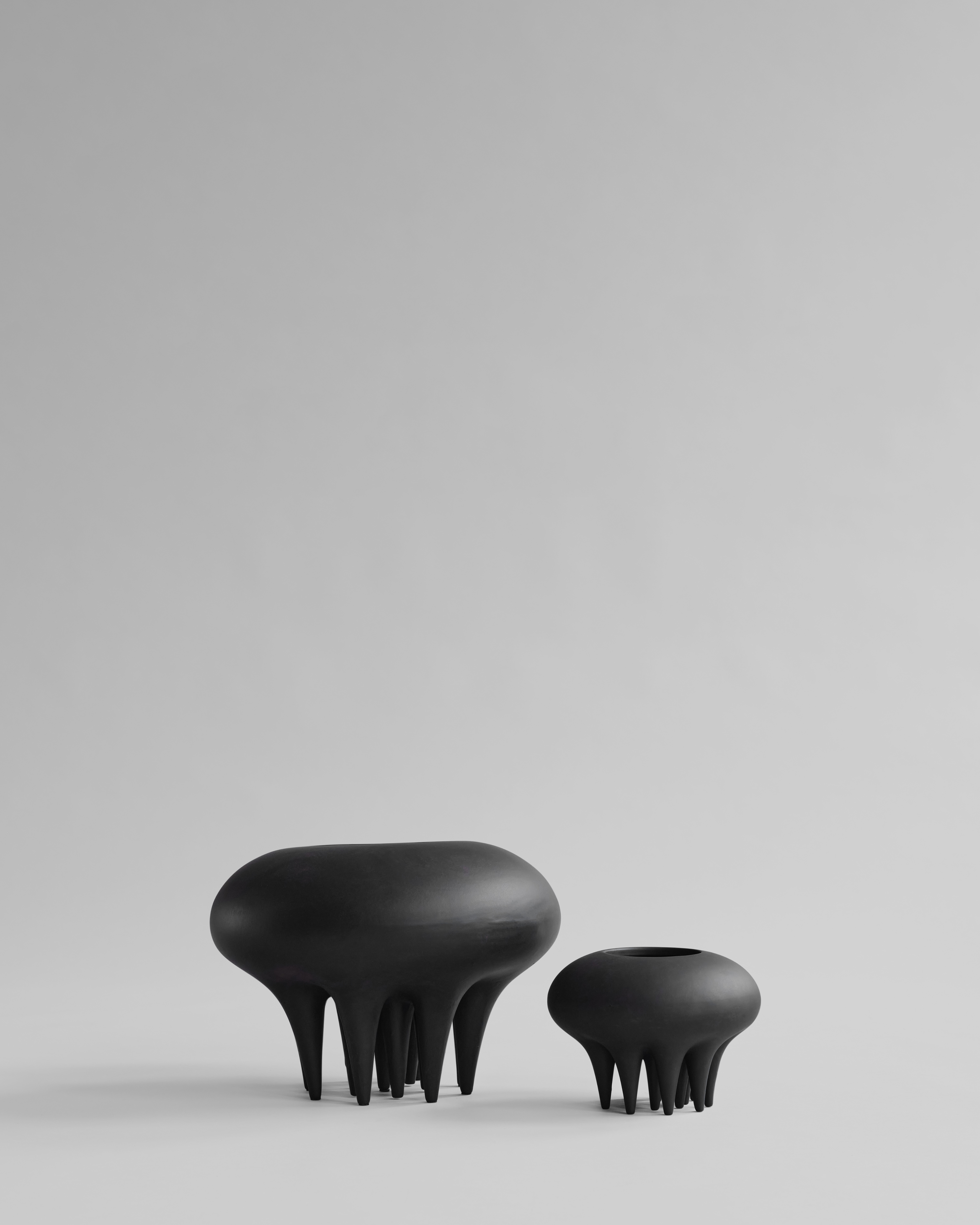 Two black, organic-shaped vases on a light gray background. Medusa Vase, Big by 101 Copenhagen. Sculptural ceramic vase with soft oval shapes and small conical legs, hand-glazed in Coffee. Curated by Numa Home for calm, modern interiors.