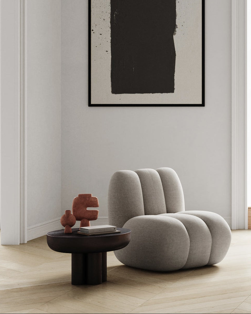 Modern interior with a unique chair, small table with art pieces on it, and abstract art on the wall.