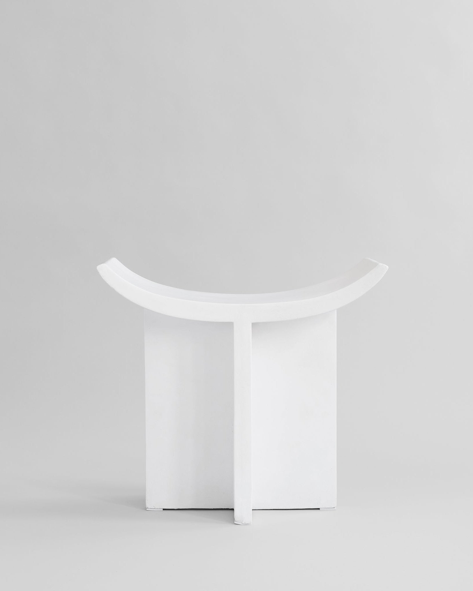 White stool with curved design on a light gray background