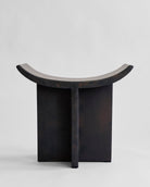 Black stone like stool with curved top on a light gray background