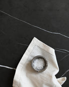 Small wooden bowl with salt on a white napkin against a dark background