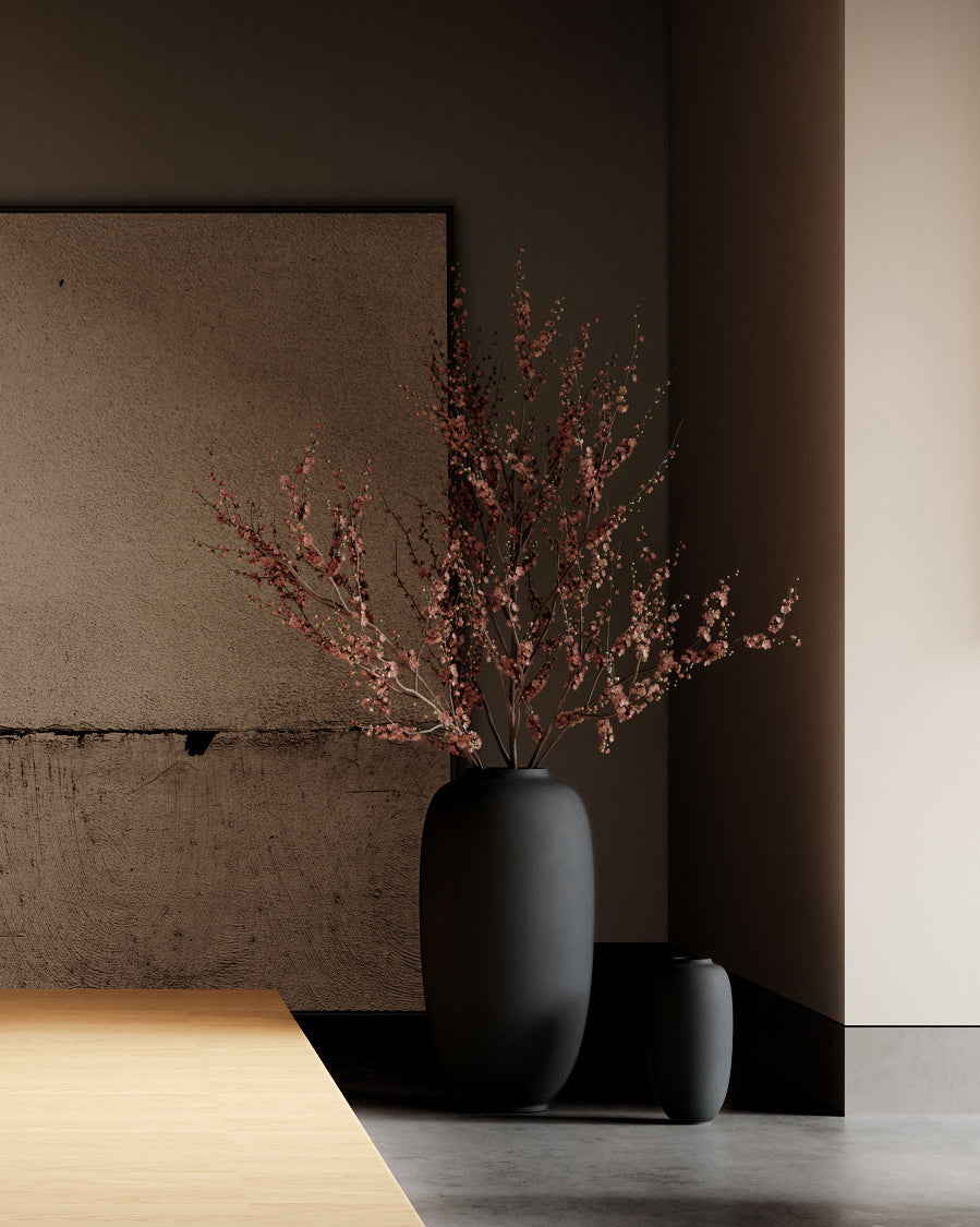 Black vase with dried branches on a wooden surface against a neutral wall. Sunao Vase Slim, Hexa by 101 Copenhagen, curated by Numa Home