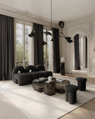 Modern living room with black furniture and large windows. Katachi Vase, Medio by 101 Copenhagen. Sculptural vase inspired by Japanese “shape”, available in High Glaze Birch ceramic and Clear or Smoked Forest mouth-blown glass. Fully waterproof – curated by Numa Home.