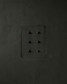 MATA recessed switch with six bullet-shaped button, seamlessly integrated into a dark green colored and rough textured plaster wall – Sumum x Studio STRAF. Curated by Numa Home for the Netherlands and Turkey