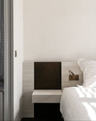 Modern bedroom with a bed and nightstand against a white wall.
