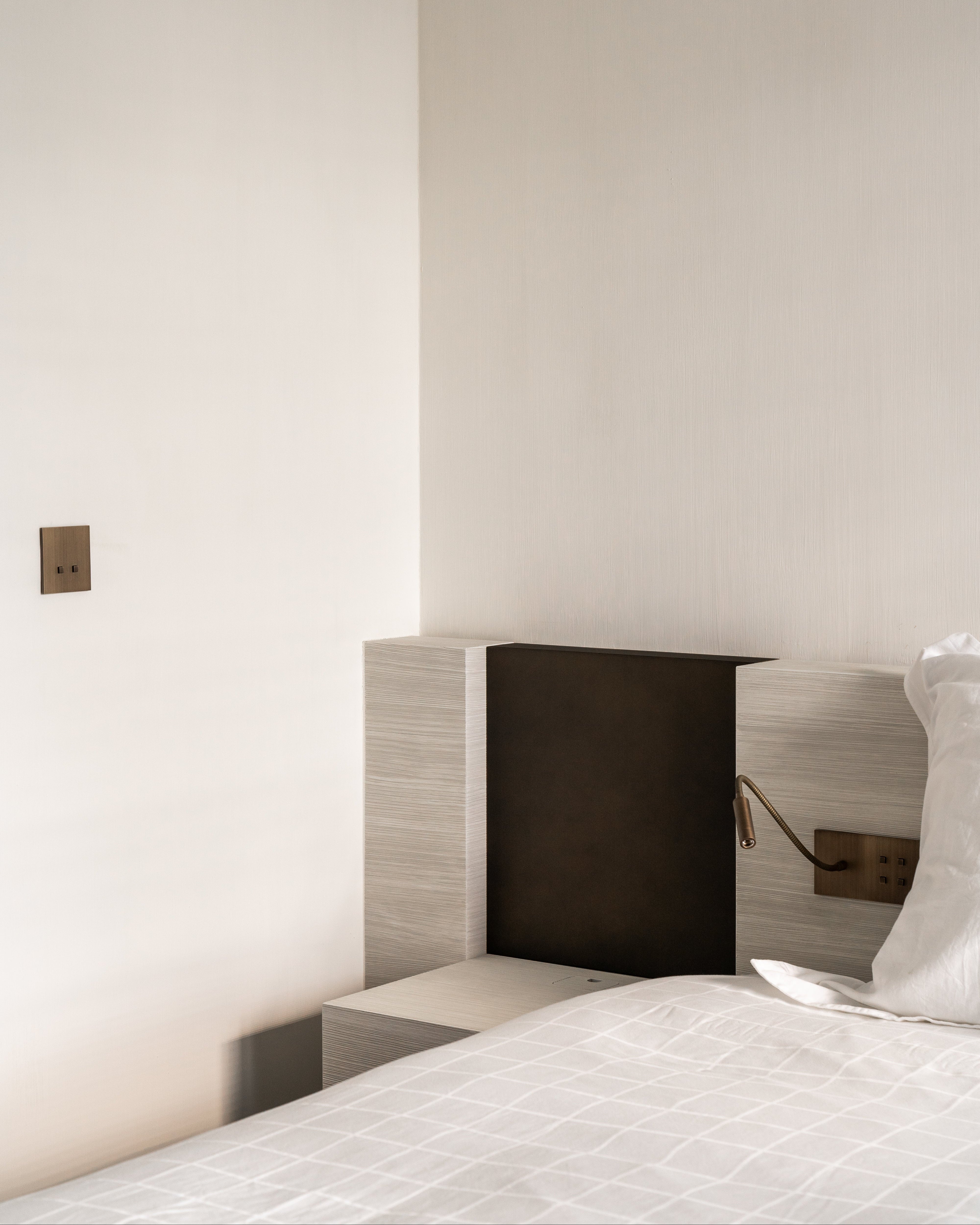 Sumum Square antique-bronze double push button and four-button switch paired with Read-S brass reading light in a custom headboard, premium hardware for luxury bedrooms provided by Numa Home