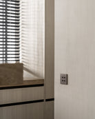 Sumum Square handcrafted brass switch in dark brushed finish, installed on a modern Dutch kitchen wall, premium custom light switch provided by Numa Home